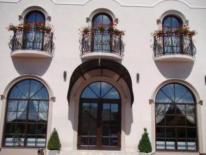 un edificio blanco con ventanas y balcones con macetas de flores en Casa Hora en Suceava
