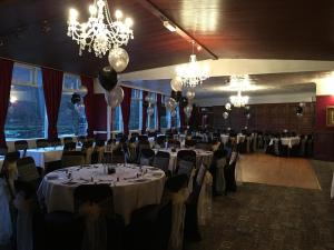 a banquet hall with tables and chairs and a chandelier at The Eagles Hotel in Llanrwst