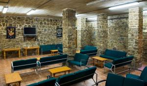 une salle d'attente avec des chaises bleues et un mur en pierre dans l'établissement Albergue Inturjoven Cortes De La Frontera, à Cortes de la Frontera