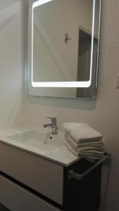 a bathroom with a sink with a mirror and towels at Gîte Le Patio in Kaysersberg