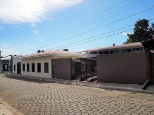 a white building with a fence and a brick street at Hotel El Viejo Inn in Chinandega