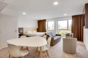 a hotel room with a bed and a table and chairs at Inspiration by balladins Caen Mémorial in Caen