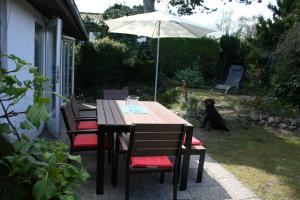 einen Holztisch mit Stühlen und einem Sonnenschirm in der Unterkunft Haus am Priwallstrand in Travemünde