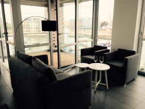 een woonkamer met banken, een tafel en ramen bij Apartment NewPort Bremerhaven in Bremerhaven