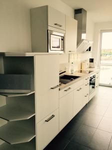 cocina con armarios blancos y microondas en Apartment NewPort Bremerhaven, en Bremerhaven