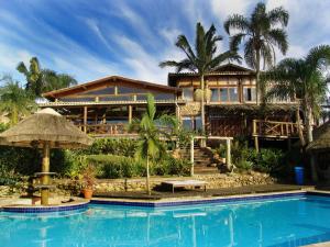 a house with a swimming pool in front of a house at Vida Sol e Mar Ecoresort in Praia do Rosa