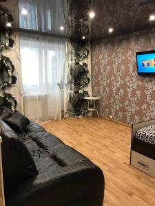 ナーベレジヌイェ・チェルヌイにあるComfortable apartmentのリビングルーム(黒い革張りのソファ、薄型テレビ付)
