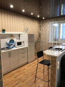 ナーベレジヌイェ・チェルヌイにあるComfortable apartmentの白いキャビネット、テーブルと椅子付きのキッチンが備わります。