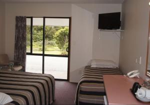 ein Hotelzimmer mit 2 Betten und einer Glasschiebetür in der Unterkunft Heritage Park Lodge in Haast