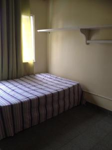 Bett in einem Zimmer mit Fenster in der Unterkunft Apartamento Cabo Frio in Cabo Frio