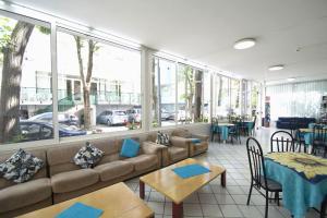 un ristorante con divano, tavoli e finestre di Hotel TV a Rimini