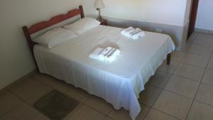 a white bed with two towels on top of it at Pousada Recanto das pedras in São Gonçalo do Rio das Pedras