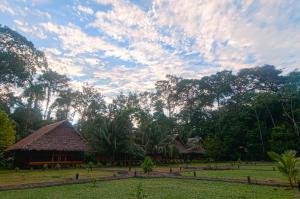 una cabaña en un campo con un cielo nublado en Amazon Field Station byInkaterra en Puerto Maldonado