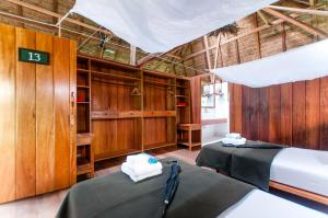 a room with two beds and wooden walls at Amazon Field Station byInkaterra in Puerto Maldonado