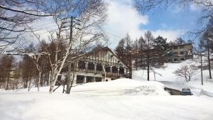 a building in the snow with a pile of snow at Chalet Madarao in Iiyama