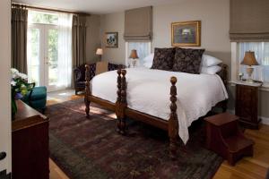 a bedroom with a large bed in a room with windows at Jackson House Inn in Woodstock