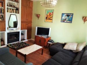a living room with a couch and a tv at Laurel Beach House in Lourinhã