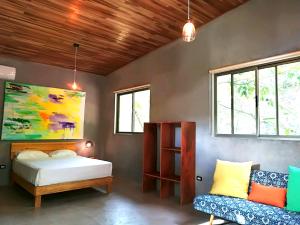 a bedroom with a bed and a couch and windows at Shakti in Santa Teresa Beach
