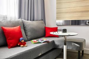 a teddy bear sitting on a couch with red pillows at Novotel Mexico City Santa Fe in Mexico City