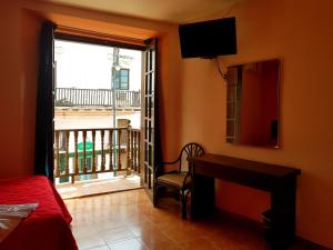 a bedroom with a bed and a desk and a balcony at Hotel Plaza Centro Historico in Veracruz