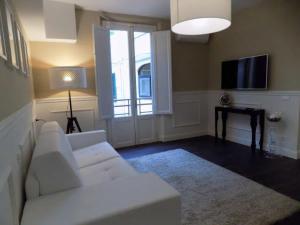 ein Wohnzimmer mit einem weißen Sofa und einem TV in der Unterkunft Hs4U The Romantic Luxury apartment in Prato