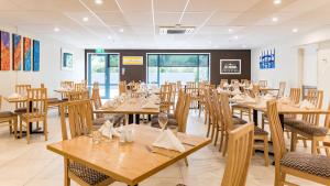 a dining room with wooden tables and chairs at Heartland Hotel Auckland Airport in Auckland