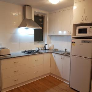 a kitchen with white cabinets and a stove top oven at Freo for Two in Fremantle