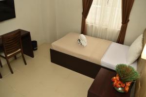 a bedroom with a bed and a chair and a table at Columbus Plaza Hotel in General Santos