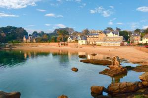 a view of a beach with houses and a body of water at Logis Hôtel Saint Guirec Et De La Plage in Perros-Guirec
