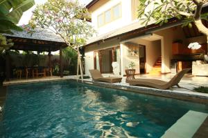 a swimming pool with chairs and a house at Desa Di Bali Villas in Kerobokan