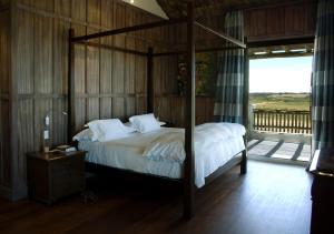 a bedroom with a canopy bed with a wooden wall at Estancia VIK José Ignacio in José Ignacio