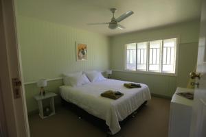 a bedroom with a bed with white sheets and a window at CedarBrae Country Stay in Gympie