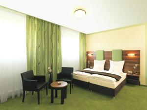 a bedroom with a bed and two chairs and a table at Hotel und Cafe Paso in Vierkirchen