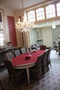 une salle à manger avec une table et des chaises rouges dans l'établissement La Porte Cochère, à Ypres