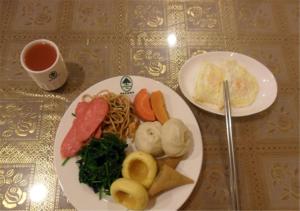 WenshangにあるGreenTree Inn Jining Wenshang Baoxiang Temple Express Hotelのテーブル(2皿分の食べ物とお茶付)