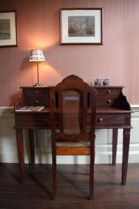 a wooden desk with a chair and a lamp on it at La Porte Cochère in Ieper