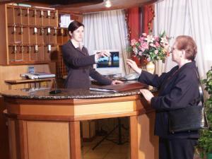 Eine Frau, die an einem Tisch steht, mit einem Mann an einem Tisch. in der Unterkunft Hotel Montereale in Pordenone