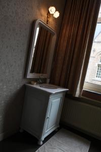 ein Bad mit einem Waschbecken, einem Spiegel und einem Fenster in der Unterkunft La Porte Cochère in Ypern