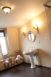 a bathroom with a sink and a mirror and two chairs at La Porte Cochère in Ieper
