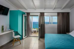 a bedroom with a blue bed and a view of the ocean at Coral Hotel in Ierápetra