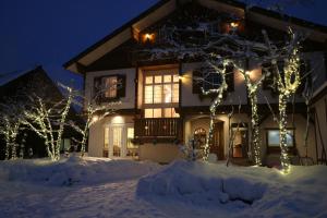 a house decorated with christmas lights in the snow at White Silver Hakuba in Hakuba