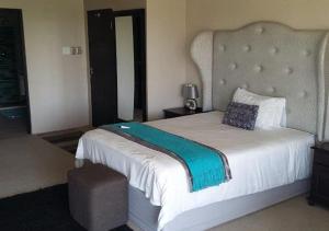 a hotel room with a bed, chair, and nightstand at Dante Deo Guesthouse in Bloemfontein