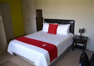 a bed with a white comforter and pillows at Dante Deo Guesthouse in Bloemfontein