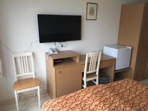 a bedroom with a bed, desk and television at Carolina Hotel in Pärnu