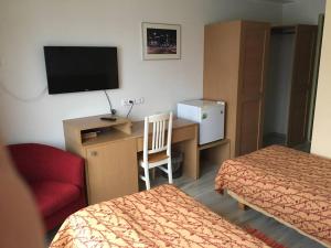 a hotel room with two beds and a desk with a television at Carolina Hotel in Pärnu