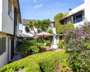 einen Garten mit Sonnenschirm, Stühlen und Blumen in der Unterkunft Carmel Fireplace Inn in Carmel