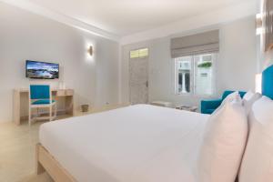 a white bedroom with a large bed and blue chairs at Epique by Epic Collection in Unawatuna