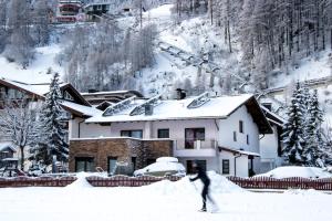 a person walking in the snow in front of a house at Linserhof Ferienappartements in Sölden