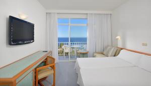 カラス・デ・マヨルカにあるAluaSun Cala Antena - All Inclusiveのベッドとテレビが備わるホテルルームです。
