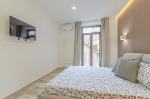 a white bedroom with a bed and a window at Dreaming Taormina Apartment in Taormina